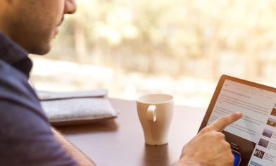a person seated with a mug and interacting with a touch screen