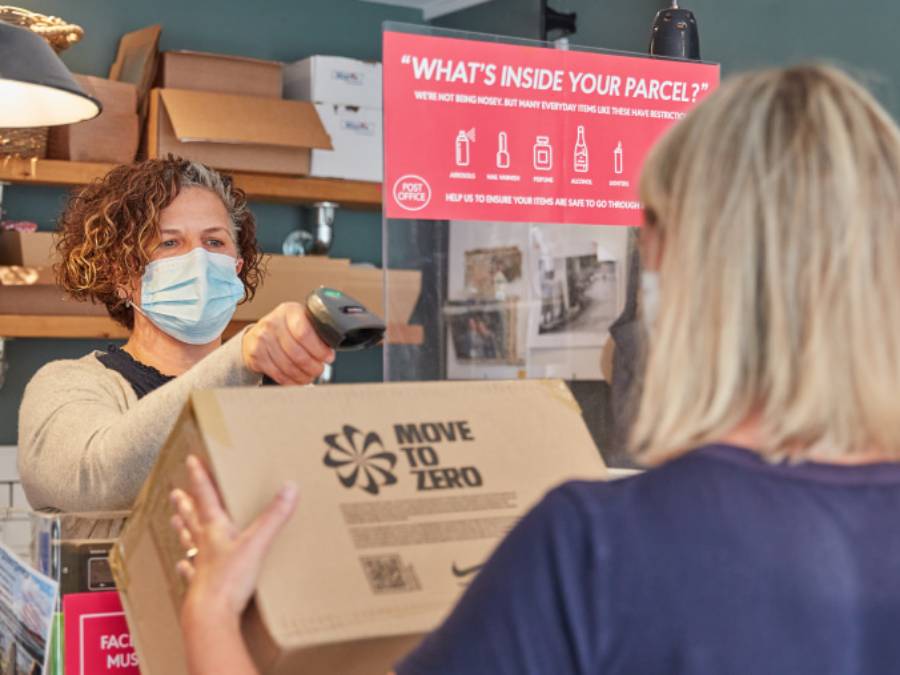 A female member of Post Office staff scanning a customers package