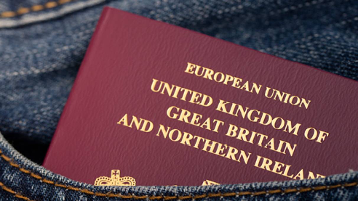 European Union passport partially sticking out of a front pocket of denim clothing