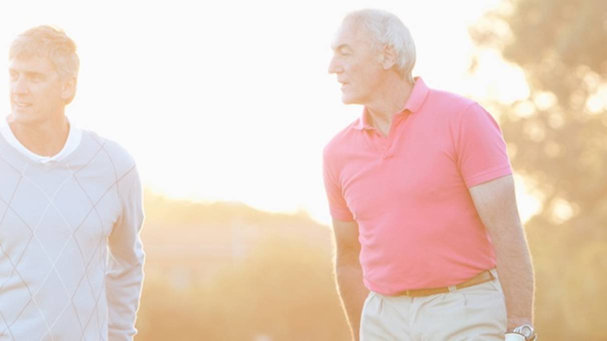 Two mature men standing outside, on a bright morning