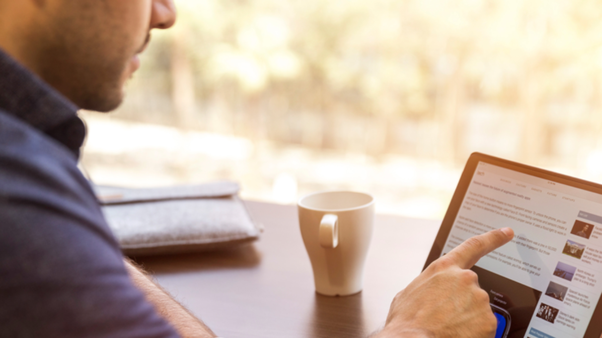 a person seated with a mug and interacting with a touch screen
