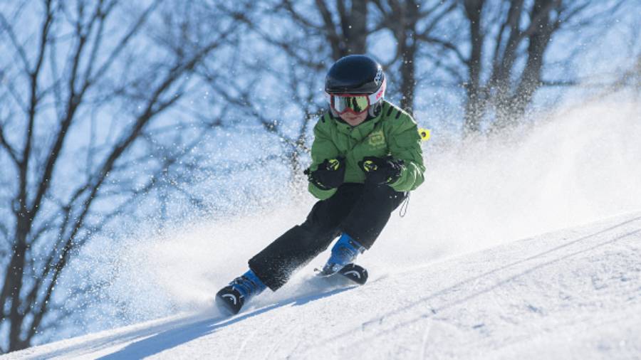Boy skiing with snow spray and trees in background