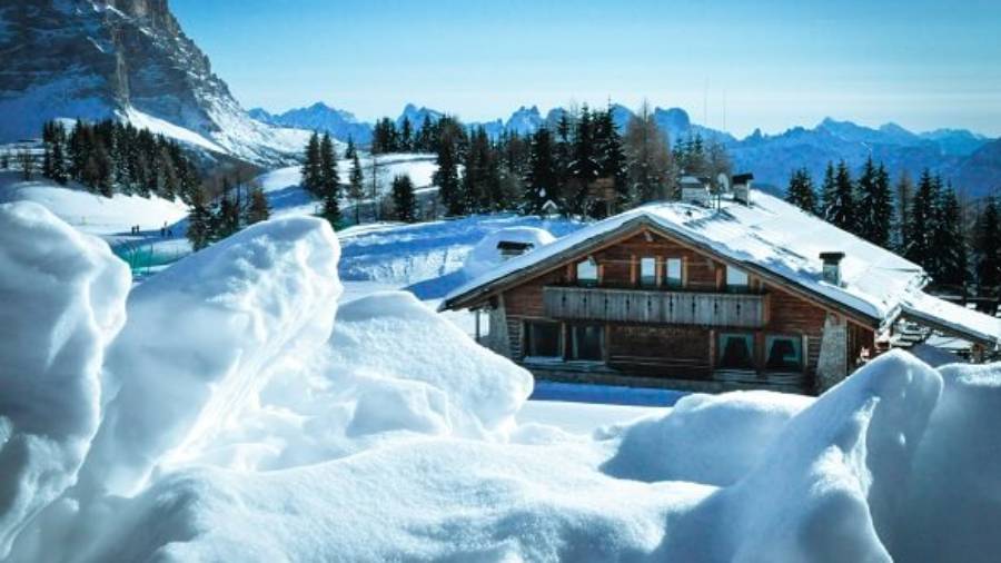 Chalet in mountains surrounded by snow and trees 