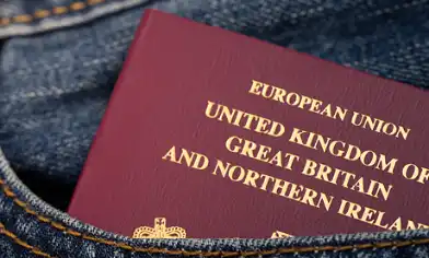 European Union passport partially sticking out of a front pocket of denim clothing