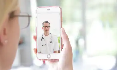 Woman holding up mobile phone, showing a doctor on the screen