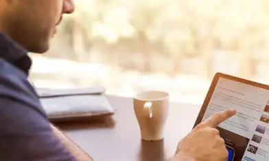 a person seated with a mug and interacting with a touch screen