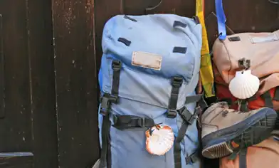 Two backpacks, one with boots attached, sat against a dark wooden door