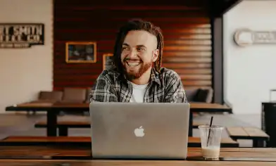 A person sitting at a table working on a laptop, in a room with modern decor.