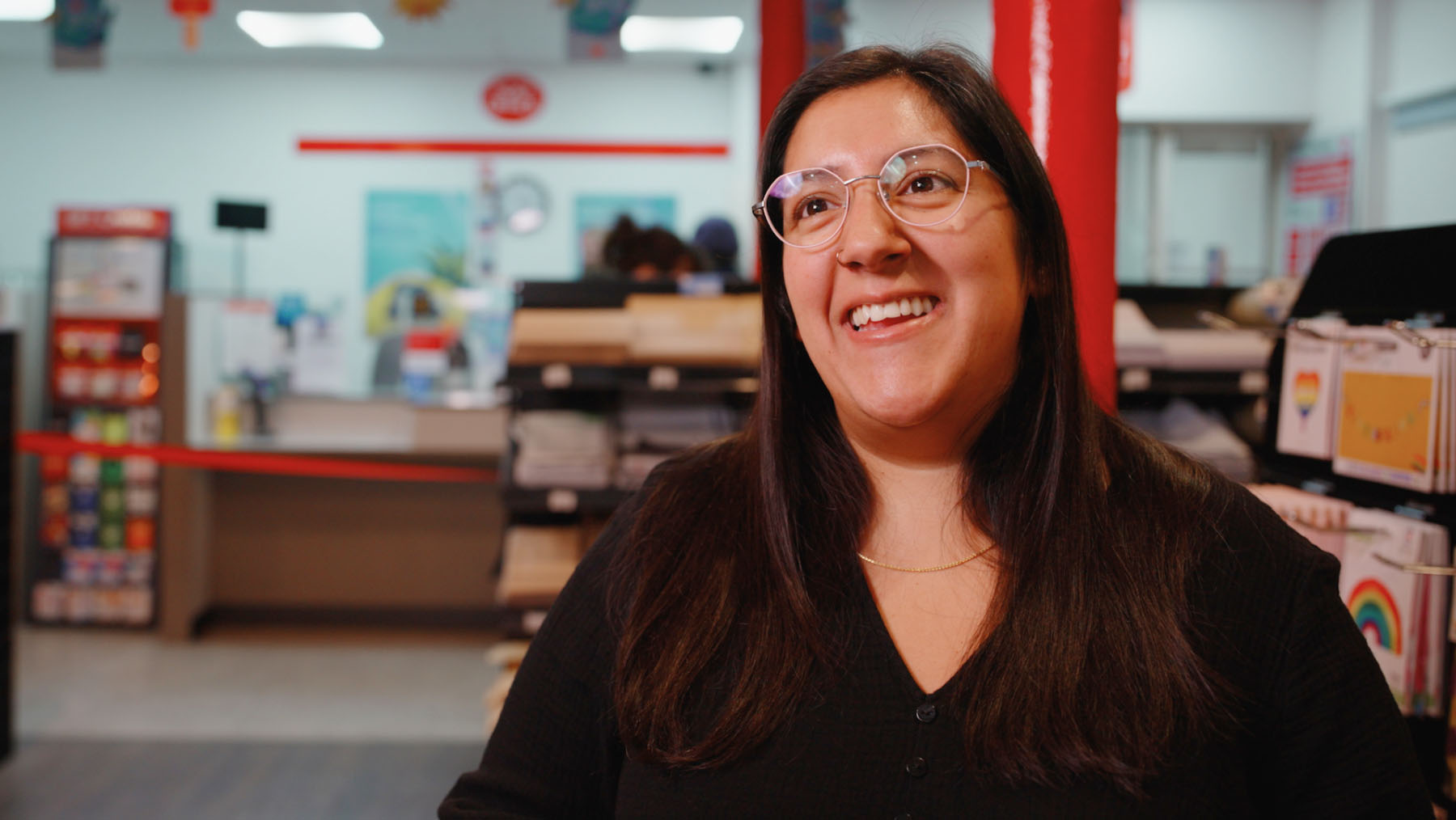 Student hub "Ask your postmaster" Smiling team member Natalie in front of the counter at one of our Glasgow Post Office branches  